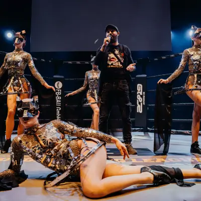 TBL Events performers in a futuristic illuminated outfit inside an MMA fight cage during a live combat sports event.