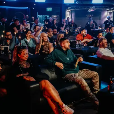 Audience enjoying a lively nightclub event with people watching the performance, surrounded by atmospheric lighting and table seating.